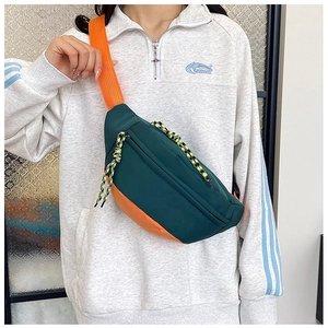 Detail of green and orange contrast crossbody waist bag with sporty bungee cord detail