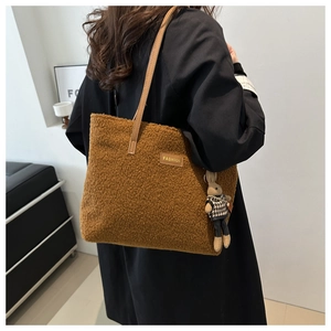 Gros plan du sac cabas en peluche marron avec étiquette en cuir et breloque lapin mignon