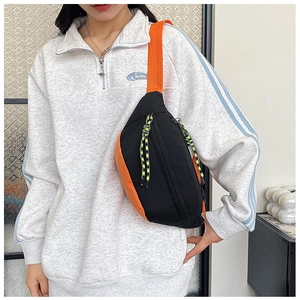 Detail of trendy black and orange fanny pack with braided zipper puller and woven strap