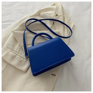 Detailed close-up of a royal blue trapezoid handbag with a leather-like texture finish