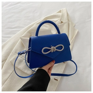 Detail of blue matte leather bag showing sparkling rhinestone bow and fine stitching