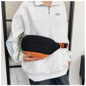 Detail of color-block waist bag in black and orange with adjustable neon strap buckle