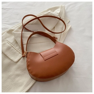 Detail view of brown crescent moon bag with smooth leather finish and gold buckle