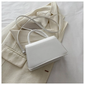 Detail of a white trapezoid handbag with minimalist stitching and matte synthetic leather