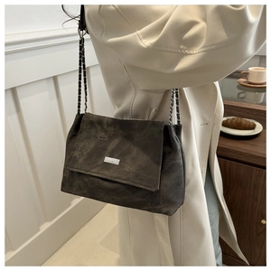 Détail du sac à bandoulière en daim gris avec chaîne porté avec un trench-coat beige