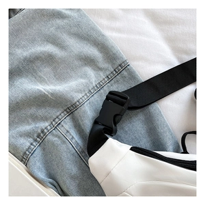 Dettaglio del marsupio bianco in nylon con fibbia in plastica nera e tracolla regolabile