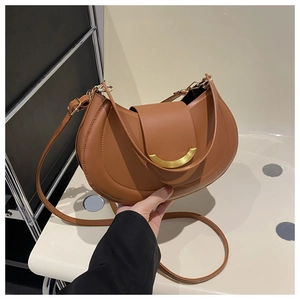 Detail of brown crescent leather bag featuring golden ring clasp and adjustable strap