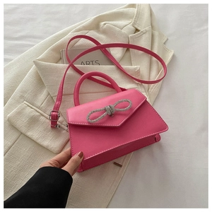 Close-up of fuchsia handbag featuring a sparkling rhinestone bow and smooth texture