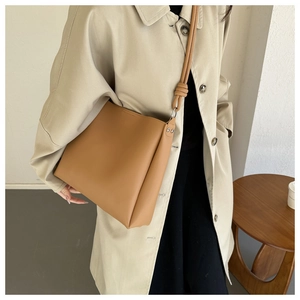 Vue latérale du sac seau en cuir PU marron avec rivets et longue bandoulière