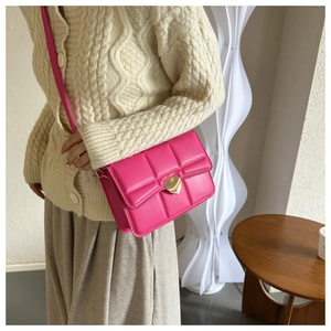 Dettaglio borsa a tracolla trapuntata fucsia con chiusura a cuore dorata e stile chic