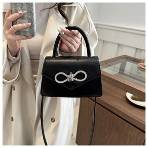 Detail of a black leather handbag with a sparkling silver rhinestone bow clasp
