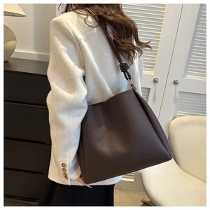 Détail du grand sac cabas en cuir marron foncé avec un nœud décoratif sur la bandoulière