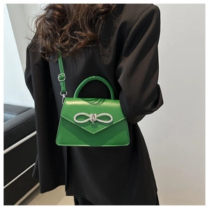 Bright green bow shoulder bag with rhinestones shown on model in black suit