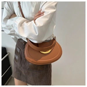 Detail of tan crescent shoulder bag with golden metallic buckle and fine leather texture