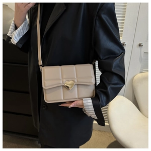 Dettaglio borsa a tracolla beige trapuntata con chiusura a scatto dorata a forma di cuore