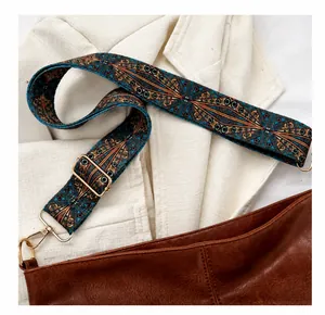 Close-up of ethnic style wide woven shoulder strap with gold metal hooks on brown bag