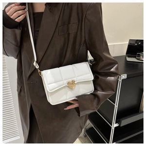 Piccola borsa trapuntata bianca con chiusura a cuore dorata indossata su una giacca