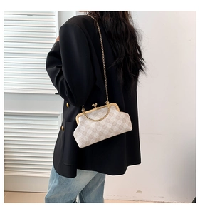 Detalle de bolso de concha a cuadros beige con cadena dorada y asa metálica en modelo