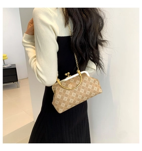 Detalle de bolso vintage con estampados de tréboles y correa de cadena dorada fina