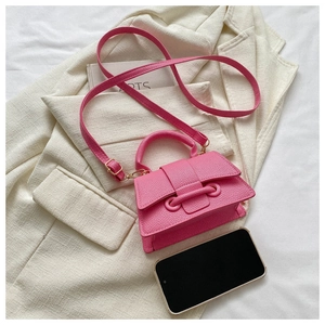 Mini-Umhängetasche aus rosa Leder mit Smartphone als Größenvergleich auf hellem Stoff