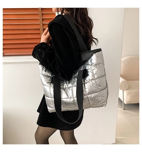 Detail of silver quilted tote bag with wide black straps and metallic finish