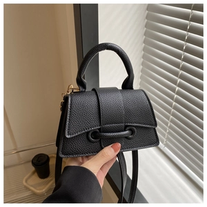 Nahaufnahme einer schwarzen Handtasche aus Leder mit goldener Schnalle und Sanduhr-Form