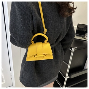 Detailansicht der gelben Mini-Tasche mit Ledertextur, Riemen und silbernen Beschlägen