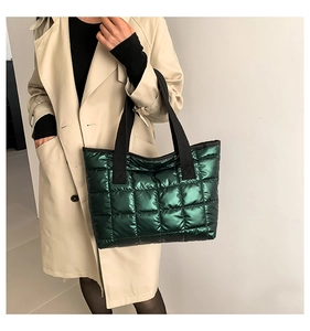 Macro detail of the dark green quilted tote bag with a metallic finish and black straps