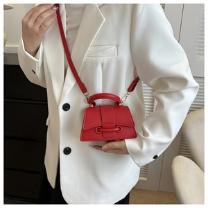 Detail der roten strukturierten Lederhandtasche mit Goldbeschlägen auf weißem Blazer