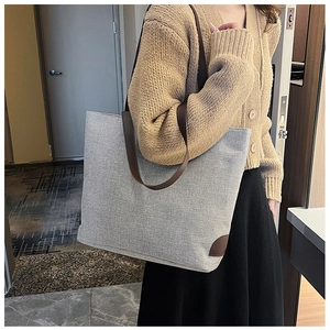 Detail of grey canvas tote bag with dark brown leather straps for daily commute