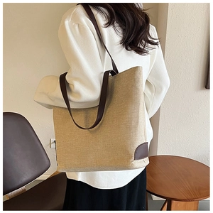 Detailed view of the large linen tote bag showing brown leather straps and reinforced corners