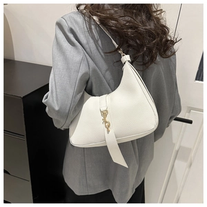 Nahaufnahme einer weißen Leder-Halbmondtasche mit goldenem Verschluss an einem Model