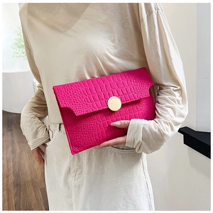 Detail of rose red envelope clutch with crocodile texture and gold round buckle