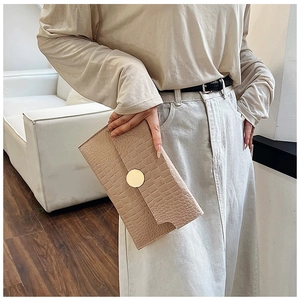 Detail of beige crocodile embossed envelope clutch with elegant gold round buckle closure