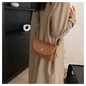 Detail of vintage brown leather crossbody bag with floral gold clasp and wide strap