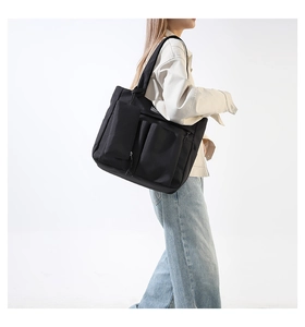 Detalle del bolso tote grande de nailon negro con múltiples bolsillos exteriores prácticos