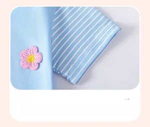 Detail of light blue girl dress with striped sleeve cuffs and pink crochet flower applique