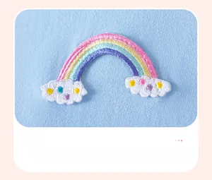 Detail of baby blue cotton dress featuring colorful rainbow embroidery and 3D cloud patches