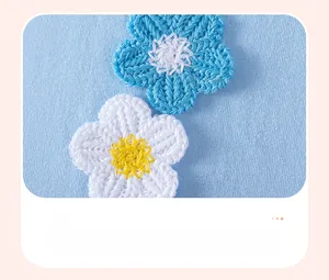 Detail of 3D crocheted flowers and intricate yellow stitching on light blue cotton knit dress