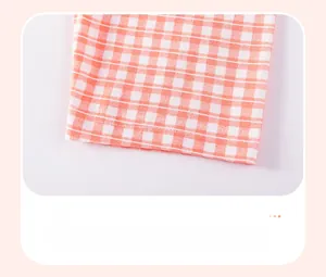 Detailed close-up of orange and white gingham pattern fabric and hem stitching on girl's set