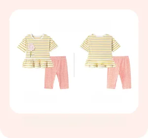 Detail view of girls summer outfit featuring striped t-shirt with floral patch and plaid pants