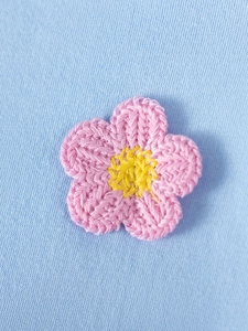 Pink crocheted flower detail on light blue knit dress with yellow stamen centerpiece