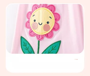Detailed close-up of a smiling sunflower applique embroidery on pink cotton girls clothing