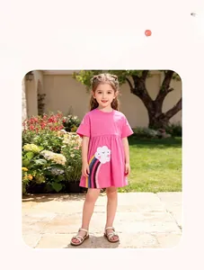 Détail de robe rose pour fille avec broderies arc-en-ciel et nuages souriants