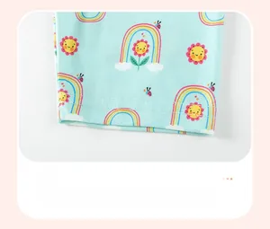 Detail of baby girl trousers leg featuring rainbow and ladybug prints on blue fabric