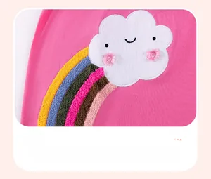 Détail de la broderie bouclée nuage et arc-en-ciel sur robe rose en coton pour enfant