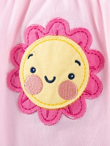 Close-up of pink cotton knit girls' top featuring a cute sunflower embroidery with smiley face