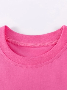 Détail du col rond et du bord-côte sur une robe rose à manches courtes pour fille