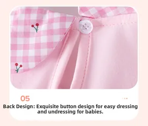 Détail de robe bébé rose en coton avec broderie cerise et bouton de fermeture au dos