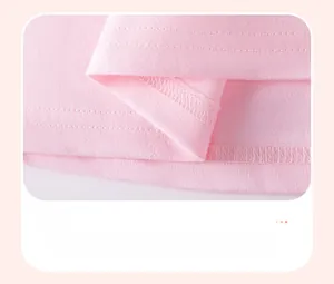 Détail des coutures doubles et de l'ourlet lisse de la robe en coton rose pâle pour enfant